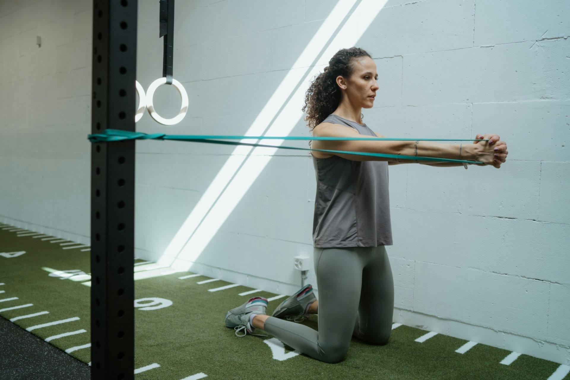 Pallof Press mit Widerstandsband. Ausübung: Band auf Brusthöhe seitlich fixieren, mit beiden Händen vor der Brust halten, Arme langsam nach vorne stre...