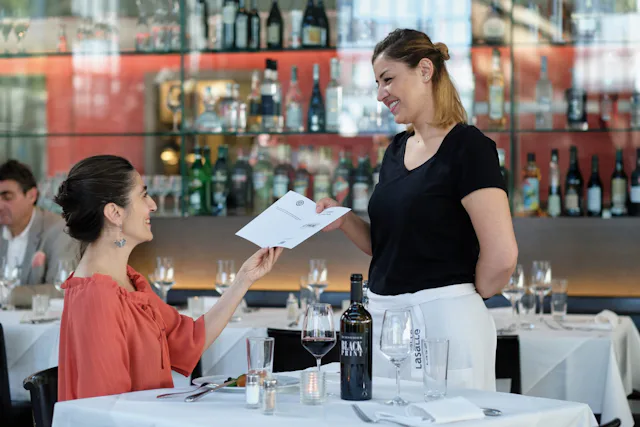 Der Fine to Dine Gutschein ist wie Bargeld. Er kann ohne Einschränkung und bei diversen Restaurants an Zahlung gegeben werden: Eine Kellnerin überreicht das Menu.